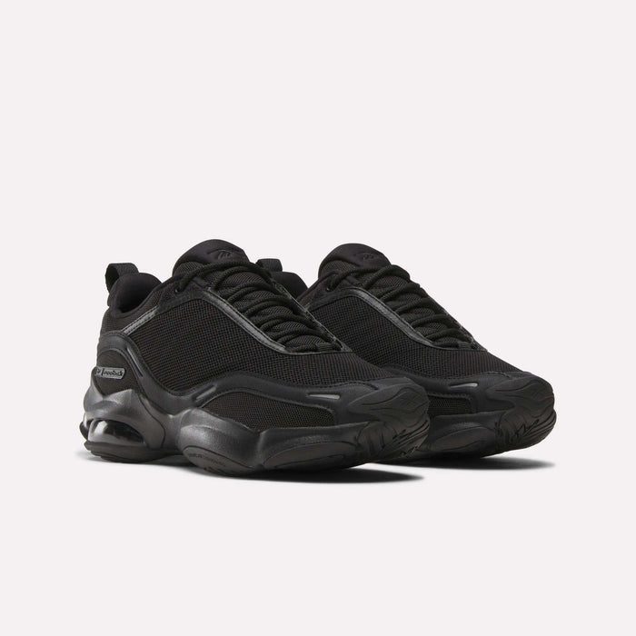 A pair of Women's DMX Series 3000 Training Shoes by Reebok in black, featuring mesh uppers, DMX 3 Technology thick textured soles, and black laces, displayed on a light background.