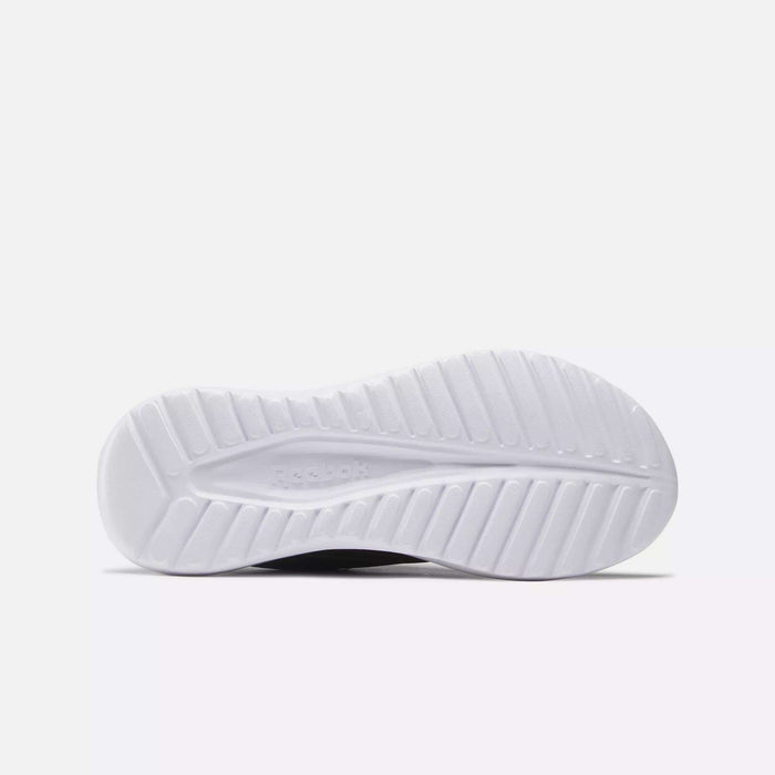 The image shows the white sole of a women's Reebok Energen Lux Running Shoe from below, featuring textured grooves for traction and an embossed "Reebok" logo in the center. The background is light gray.