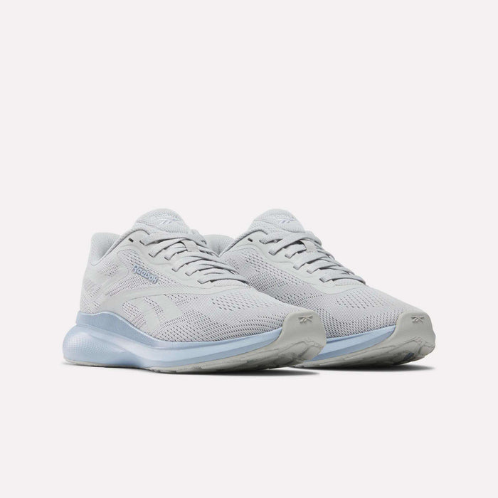 The Reebok Women's Energen Run 4 Running Shoes in light gray feature breathable mesh uppers, lace-up closures, and thick translucent soles, shown on a white background.