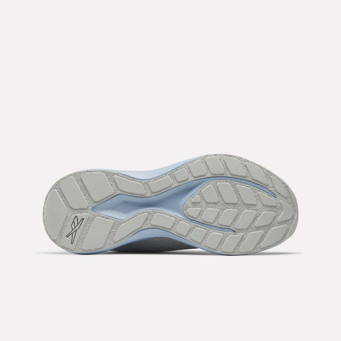 Bottom view of a light gray Reebok Women's Energen Run 4 Running Shoe sole, featuring textured and smooth patterns, a stylized logo near the heel, angular tread for grip, all on a plain white background.