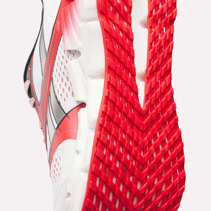 Close-up of the sole and side of Reebok Women's FloatZig 2 AHA Running Shoes in white with red and black accents, featuring a textured red outsole, breathable mesh upper with red details, and energy-returning cushioning for comfort.