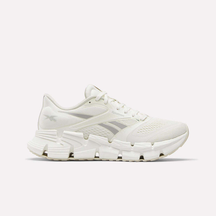 Side view of a white Reebok Women's FloatZig 2 Running Shoe featuring a mesh upper, unique angular outsole, and energy-return cushioning for comfort.