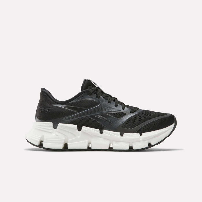 The Women's FloatZig 2 Running Shoes by Reebok are black, feature mesh and synthetic overlays, a chunky white segmented sole with Superfloat+ cushioning, and are shown from the side on a plain white background.