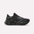 The Reebok Women's FloatZig 2 Running Shoes feature a black mesh upper, sleek design, and chunky segmented sole with Superfloat+ cushioning for energy return, shown in a side view against a white background.