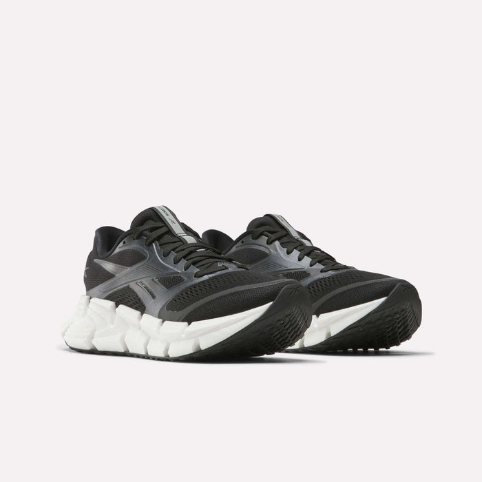 The Reebok Women's FloatZig 2 Running Shoes, in black and gray with white chunky textured soles and Superfloat+ cushioning, are displayed against a plain white background.