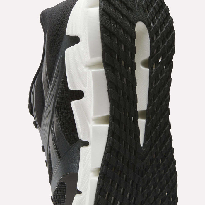 Close-up view of the sole of the Reebok Women's FloatZig 2 Running Shoes, featuring a white midsole, textured black outsole, Superfloat+ cushioning, and detailed tread pattern with signature side design.