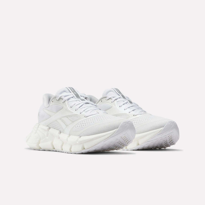 A pair of Reebok Women's FloatZig 2 Running Shoes in white, featuring thick textured soles with Superfloat+ cushioning and mesh details, displayed side by side on a light background.