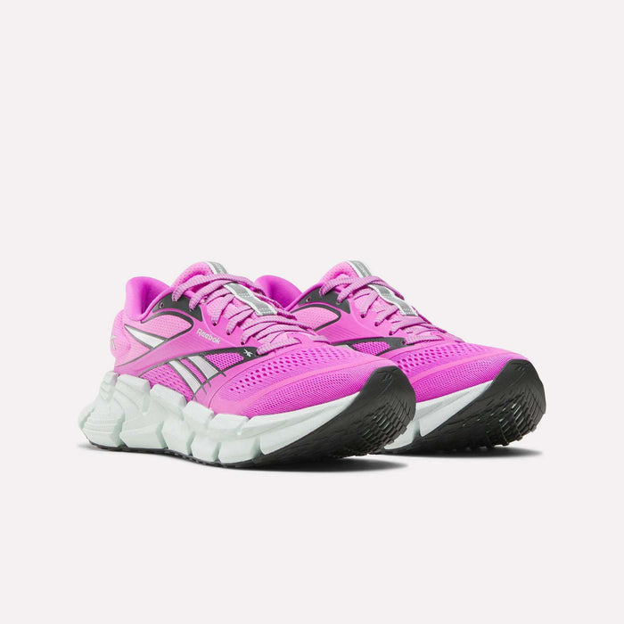 A pair of Reebok Women's FloatZig 2 Running Shoes in bright pink with energy-returning cushioning, white soles, black accents, and silver details, displayed side by side on a plain white background.