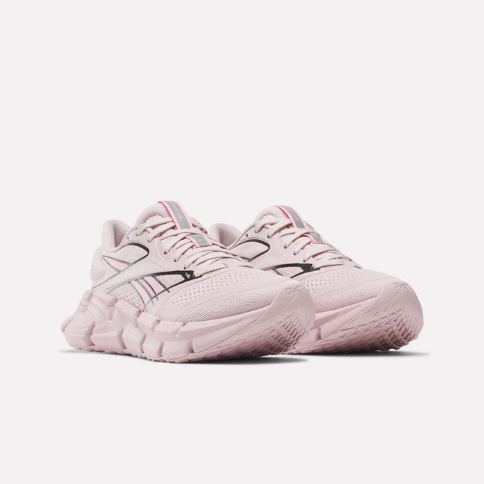 The Reebok Women's FloatZig 2 Running Shoes feature chunky, sculpted soles, black side accents, and Superfloat+ cushioning for comfort. Shown in light pink against a plain white background.