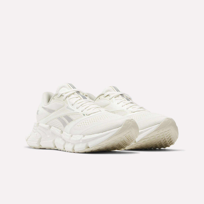 A pair of Reebok Women's FloatZig 2 Running Shoes in white with mesh uppers, textured soles, light gray accents, and energy-returning cushioning shown side by side on a plain white background.