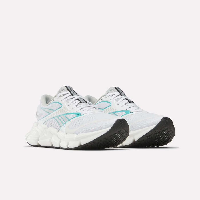 A pair of Reebok Women's FloatZig 2 Running Shoes with white uppers, light blue accents, black soles, and a chunky Superfloat+ midsole are positioned side by side on a plain white background.
