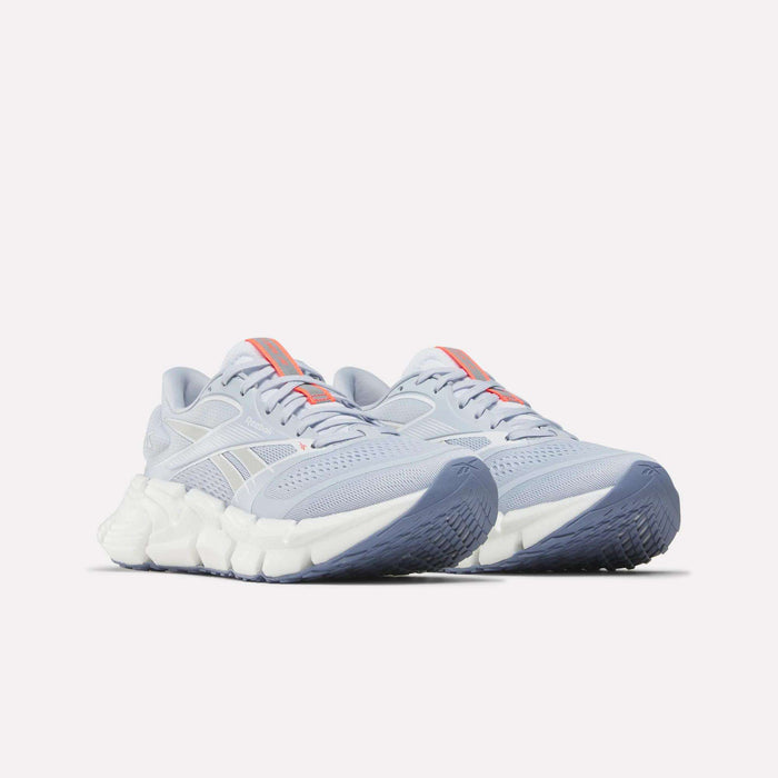 Women's FloatZig 2 Running Shoes by Reebok in light gray feature Superfloat+ cushioning, chunky white soles, light blue outsoles, and orange accents on the tongue and side, shown against a plain white background.