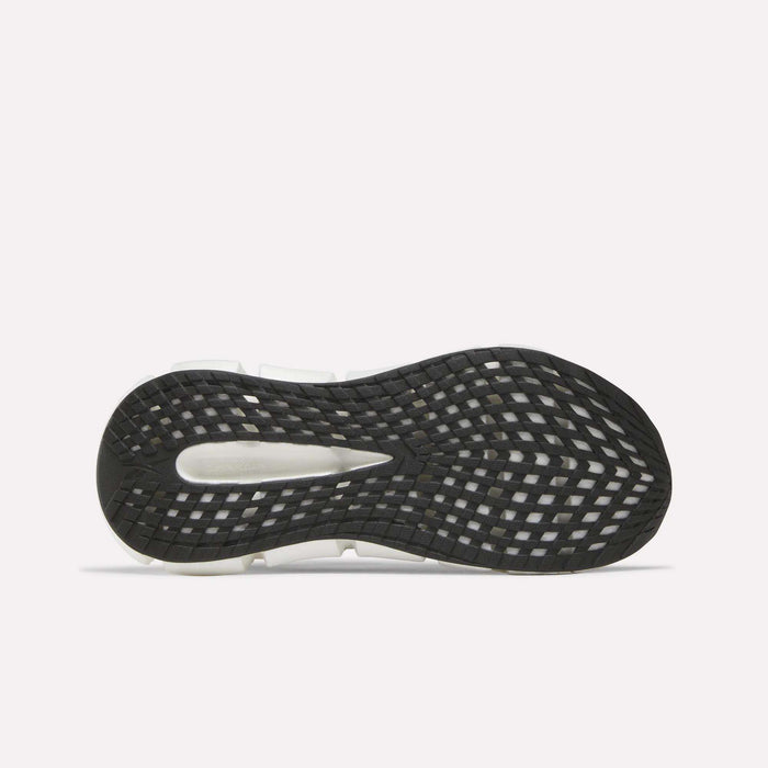 The image displays the black rubber outsole of Reebok Women's FloatZig 2 Running Shoes with a grid tread and white segments for traction and flexibility, set against a plain white background to highlight Superfloat+ cushioning comfort.