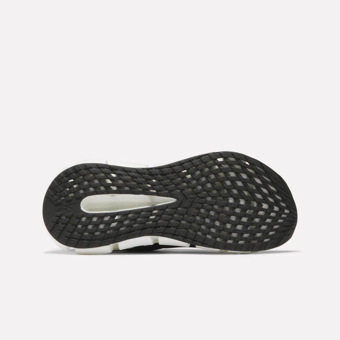 A close-up of the bottom sole of Reebok Women's FloatZig 2 Running Shoes shows a black, textured tread with a cutout revealing the lighter Superfloat+ cushioning midsole underneath.