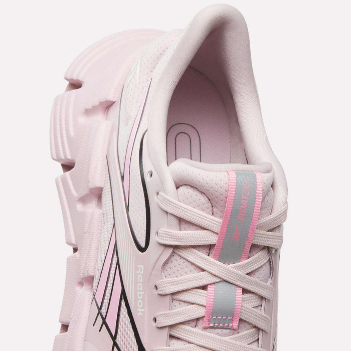 A close-up top view of the Reebok Women's FloatZig 2 Running Shoes in light pink, featuring chunky textured soles, black accents, a pink and gray tongue, Superfloat+ cushioning, breathable mesh, and white laces for comfort on your run.