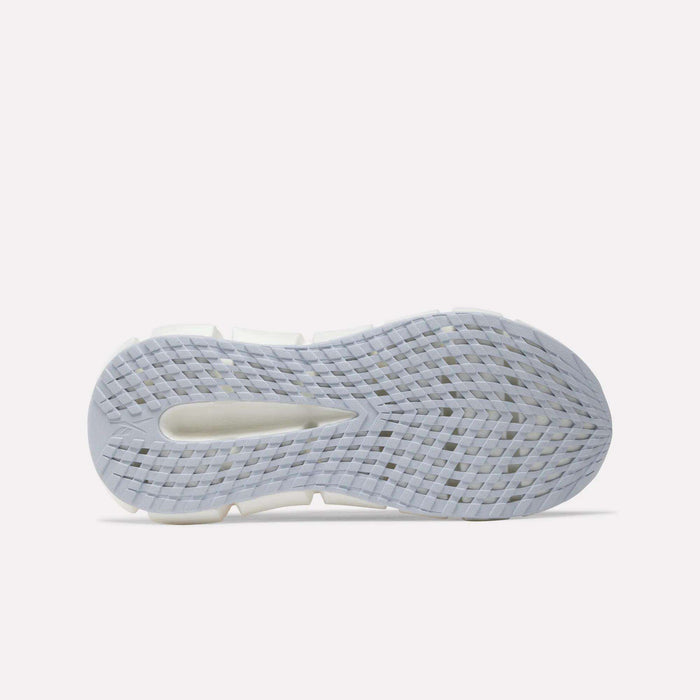 The image displays the white, textured sole of a Women's FloatZig 2 Running Shoe by Reebok, viewed from below and highlighting its grid-like tread pattern and oval cutout near the heel—signature features of this shoe designed to deliver a springy ride.
