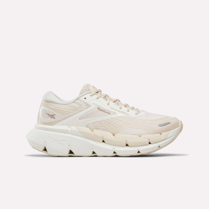 The Reebok Women's FloatZig Double Running Shoes in Chalk/Chalk/Brown feature a mesh and synthetic upper, subtle branding, and a chunky white textured sole for cushioned comfort, displayed on a plain white background.