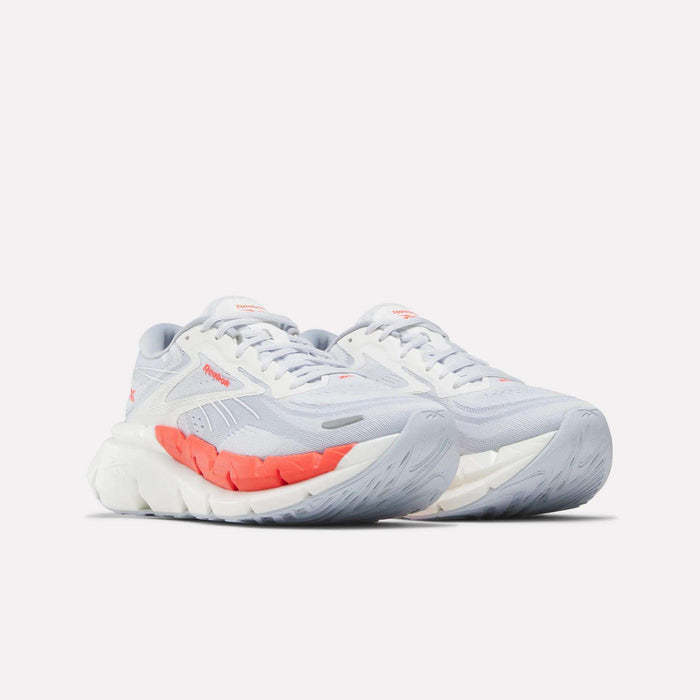 The Reebok Women's FloatZig Double Running Shoes feature light gray cushioning, thick white soles, and orange accents on the sides and tongue. Designed for comfort and support, they're subtly branded and displayed on a white background.