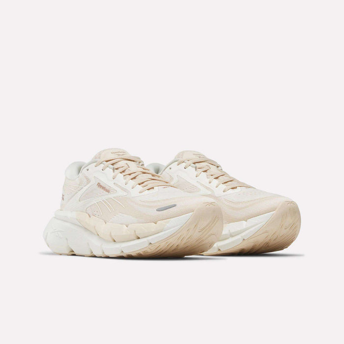 A pair of Reebok Women's FloatZig Double Running Shoes in beige and off-white with thick, textured soles and subtle branding, shown on a white background—crafted for maximum cushioning and comfort during your runs.