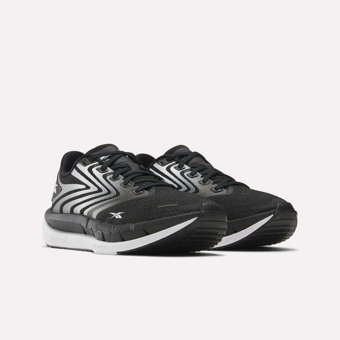 A pair of Reebok Women's FloatZig Tread Running Shoes in black and white, featuring breathable mesh uppers, zigzag side details, white soles, and Reebok branding—ideal for treadmill workouts—shown on a plain white background.