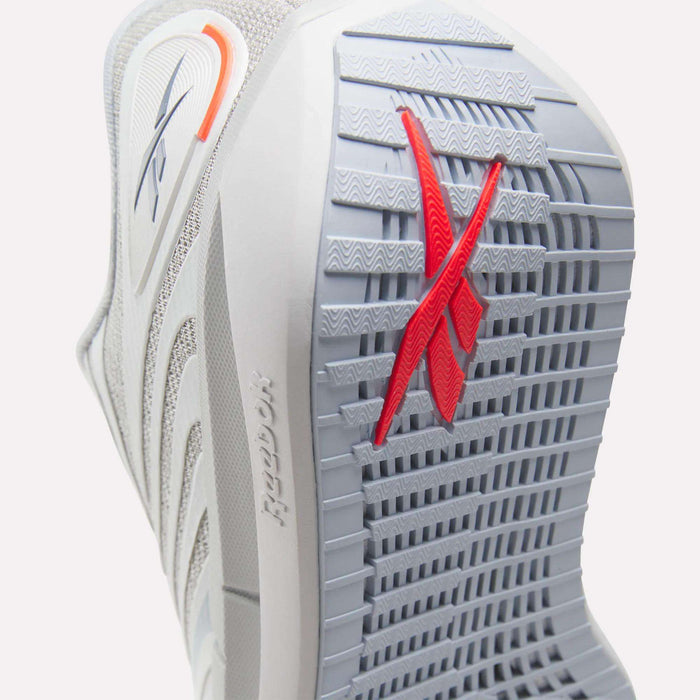 Close-up of the sole of Reebok Women's FloatZig Tread Running Shoes in gray, showing a textured grip ideal for treadmill use and a red Reebok logo. Also visible: breathable mesh upper, side branding, and heel detail.