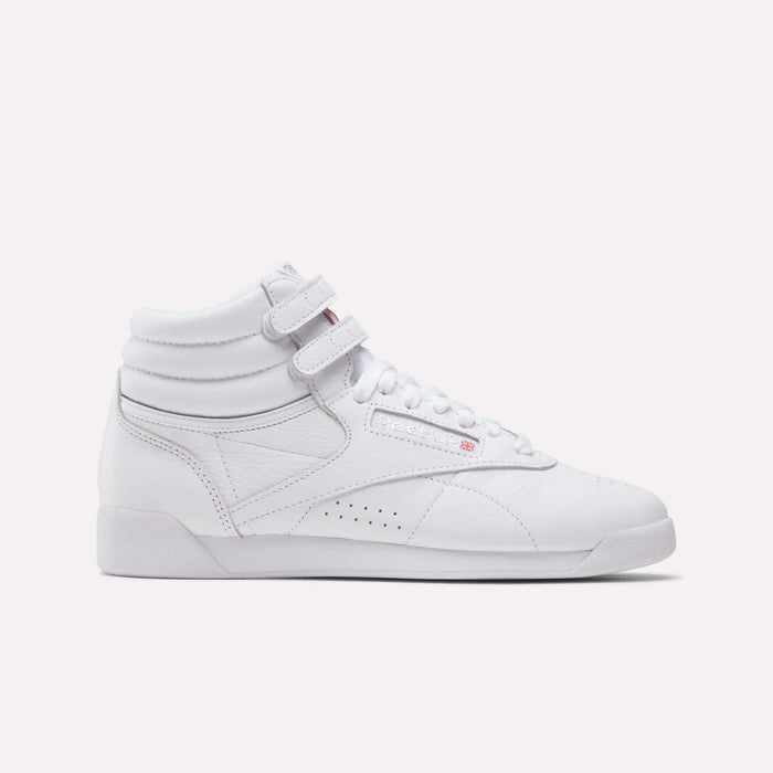 The Women's Freestyle Hi Shoes by Reebok feature a white high-top design with two velcro ankle straps, white laces, and a textured sole—perfect for women's fitness, shown on a plain white background.