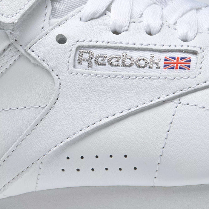 Close-up of the Women's Freestyle Hi Shoes by Reebok, showcasing the stitched logo, Union Jack flag, and crisp white laces—ideal for women who value both style and comfort in their fitness footwear.