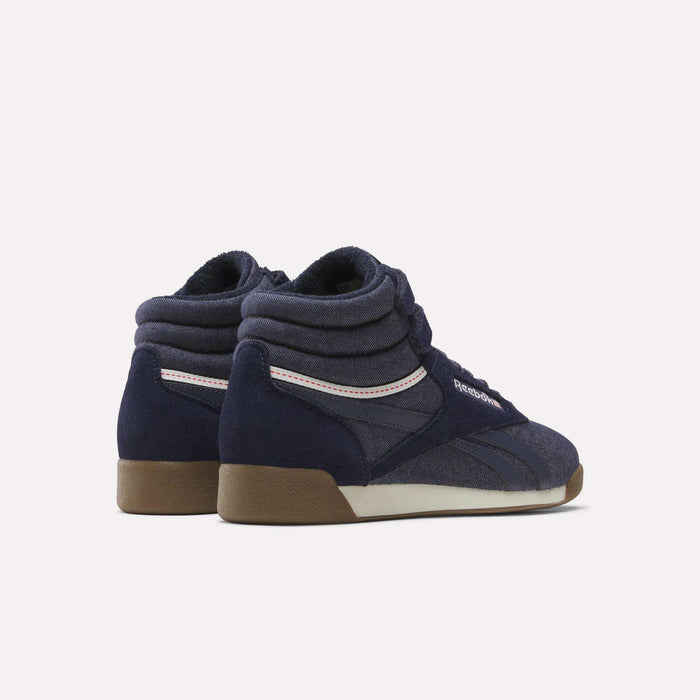A pair of Women’s Freestyle Hi Shoes by Reebok in navy blue, featuring brown soles, white accents, and padded collars with a vintage denim-inspired look, displayed on a plain light background.