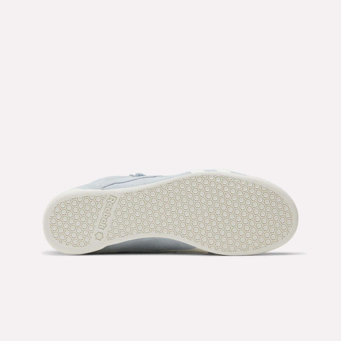The underside of a light gray Reebok Women's F/S Hi Shoe features a white rubber sole with a hexagonal tread, suede upper accents, and the Reebok logo near the heel.