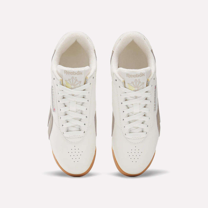 A pair of Women's Freestyle Lo Shoes by Reebok with white uppers, beige side panels, and gum soles is viewed from above on a plain light background. The Reebok logo appears on the tongues and sides of these classic sneakers.