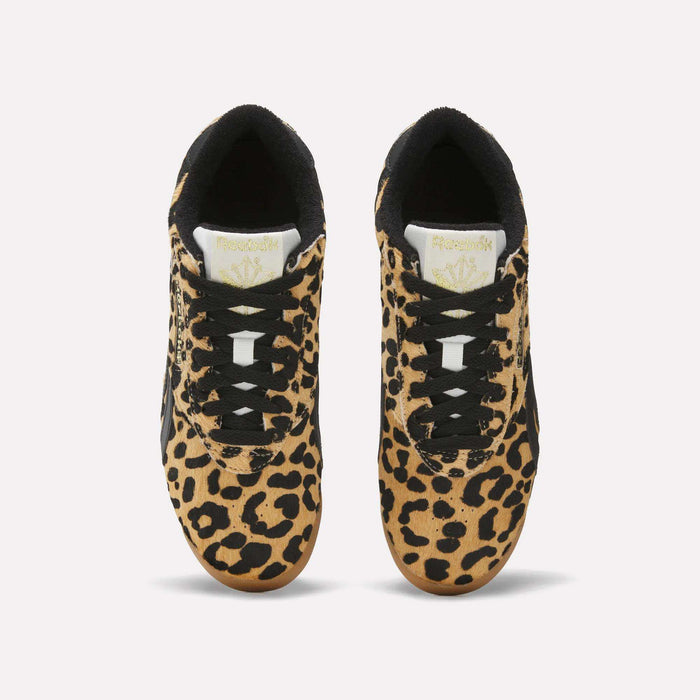 A pair of Reebok Women's Freestyle Lo Shoes with a bold leopard print pony hair upper, black laces and accents, and white tongues featuring the gold Reebok logo, inspired by classic '80s fitness trainers, viewed from above on a white background.