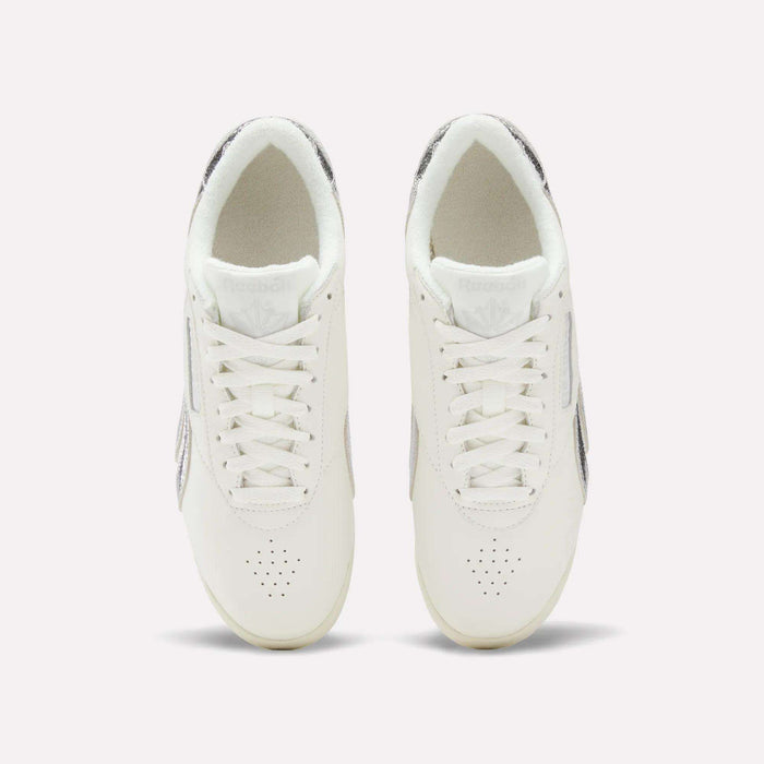 Top view of Reebok Women's Freestyle Lo Shoes with laces and subtle metallic accents on the sides and heel, displayed against a simple light background.