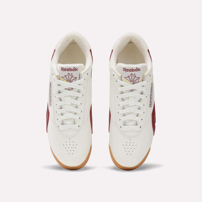 Top view of Women's Freestyle Lo Shoes by Reebok in white with maroon accents, gum soles, and logo with red maple leaf on the tongue. These women's retro sneakers are neatly laced and set side by side on a light background.