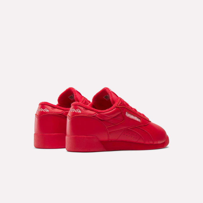 The Reebok Women's Freestyle Lo Shoes are shown in bright red with a low-top design, tonal stitching, leather material, and the Reebok logo on the heel and side against a plain light background.