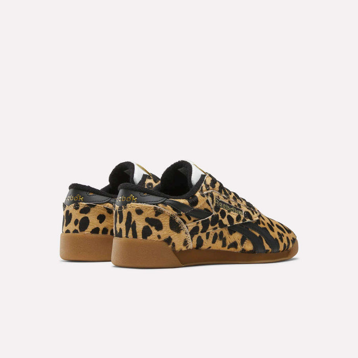 The Reebok Women's Freestyle Lo Shoes feature a bold leopard print pony hair upper, black accents, and gum rubber soles. They are shown from the back and side angles against a plain white background.
