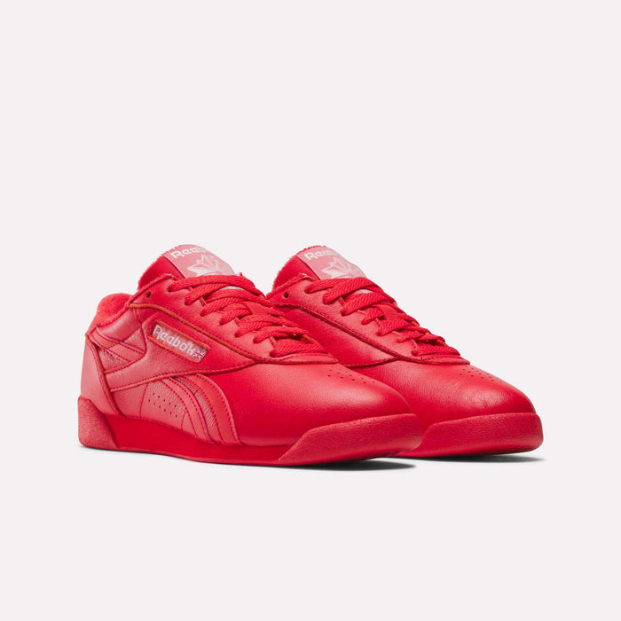 The Women's Freestyle Lo Shoes by Reebok are shown in bright red with a low-top design and white branding on the tongue and side—stylish and comfortable footwear for women, displayed against a plain white background.