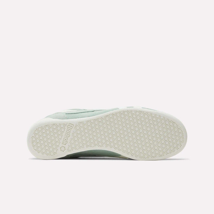 Bottom view of the Women's Freestyle Lo Shoes by Reebok in light green, showing a white rubber sole with a hexagonal pattern and embossed Reebok logo near the heel—ideal for retro sneaker enthusiasts.