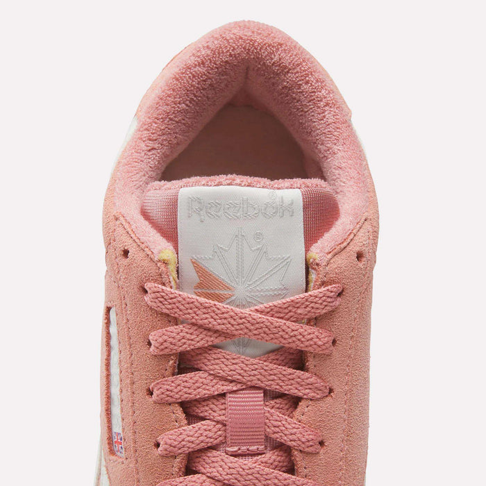 Close-up top view of Reebok Women's Freestyle Lo Shoes in pink suede, featuring pink laces, a white tongue with the Reebok logo, and a soft inner lining—showcasing classic retro sneaker details.
