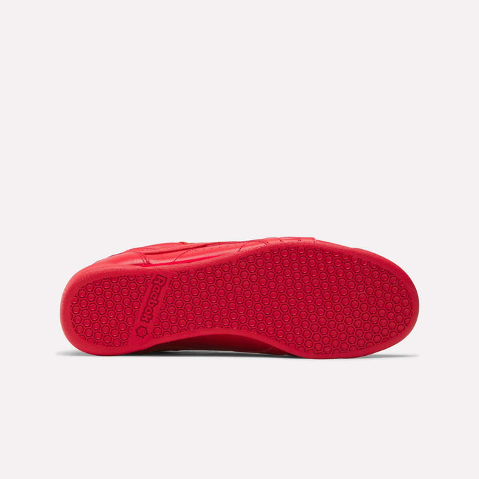 Red Women's Freestyle Lo Shoes from Reebok shown from the bottom, featuring a textured rubber sole with a hexagonal pattern and the Reebok logo near the heel. Perfect addition to any women's shoe collection. White background.