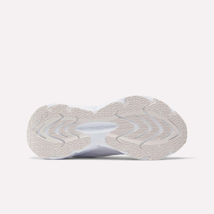 The image shows the sole of a white Reebok Women's Fuel Flex Run Shoe with a beige, wavy tread and zigzag details, viewed from below against a light background, emphasizing the cushioning Fuel Flex midsole.