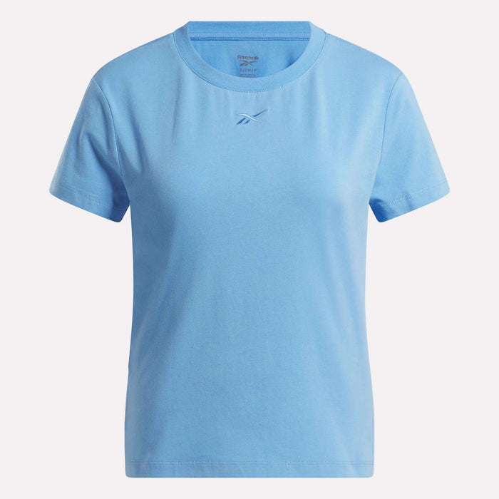 The Reebok Women's Graphic Glow Top is a light blue, short-sleeve shirt featuring a small embroidered logo at the center chest and a plain design with no other patterns.