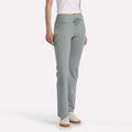 A person models Reebok Women's Highstreet High-Rise Pants in light gray, paired with a white fitted shirt and white sneakers, standing against a plain white background. The model's face is not shown.