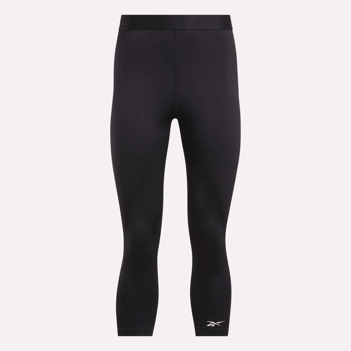 Reebok Women's ID Basketball 3/4 Compression Leggings feature a mid-rise waistband, three-quarter length, and a white logo on the lower left leg. Made from moisture-wicking fabric for comfort. Displayed on a plain light background.