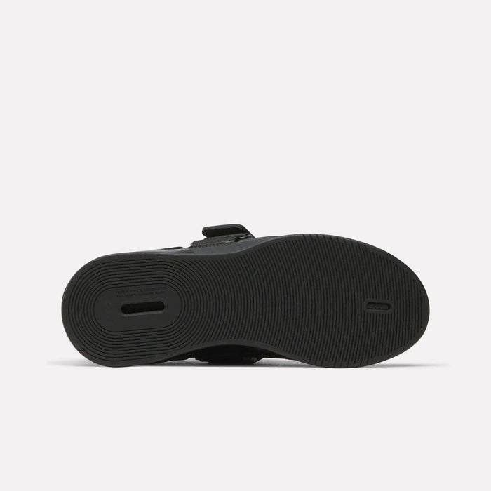 The image displays the black rubber sole of Reebok Women's Legacy Lifter IV Training Shoes, with a textured circular tread and a rectangular heel cut-out for support. The shoe is shown sole-up on a plain white background.
