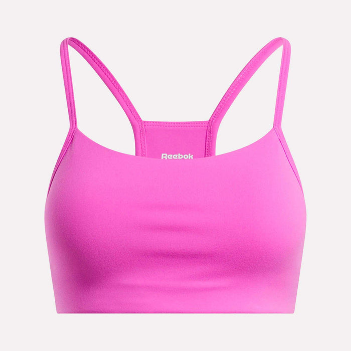The Reebok Women's Low-Impact Sports Bra is bright pink with thin adjustable straps and a smooth, simple design. The white Reebok logo appears on the front center. Ideal for light-impact training.