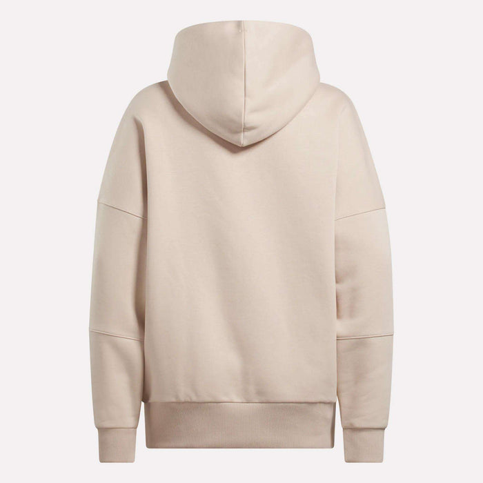 The Reebok Women's Lux Hoodie in beige features an oversized fit, long sleeves, large hood, and ribbed cuffs and waistband, shown from the back against a plain white background.
