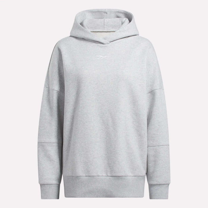 The Reebok Women's Lux Hoodie is light gray with long sleeves, ribbed cuffs and hem, and a small white chest logo. This oversized hoodie has a relaxed fit, no visible drawstrings, and offers a cozy everyday style.
