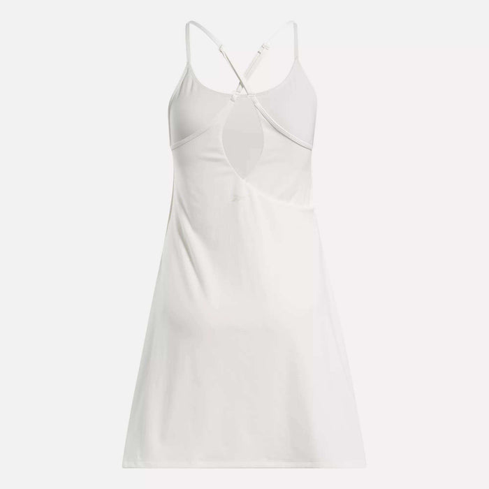 The Reebok Women's Lux Strappy Dress is a sporty, sleeveless white dress with thin crisscross adjustable back straps and a keyhole cutout below the shoulder blades, shown on a plain white background.