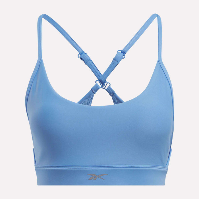 The Reebok Women's Lux Strappy Sports Bra in light blue features thin adjustable crisscross straps, sweat-wicking stretchy fabric, and a subtle front underband logo.