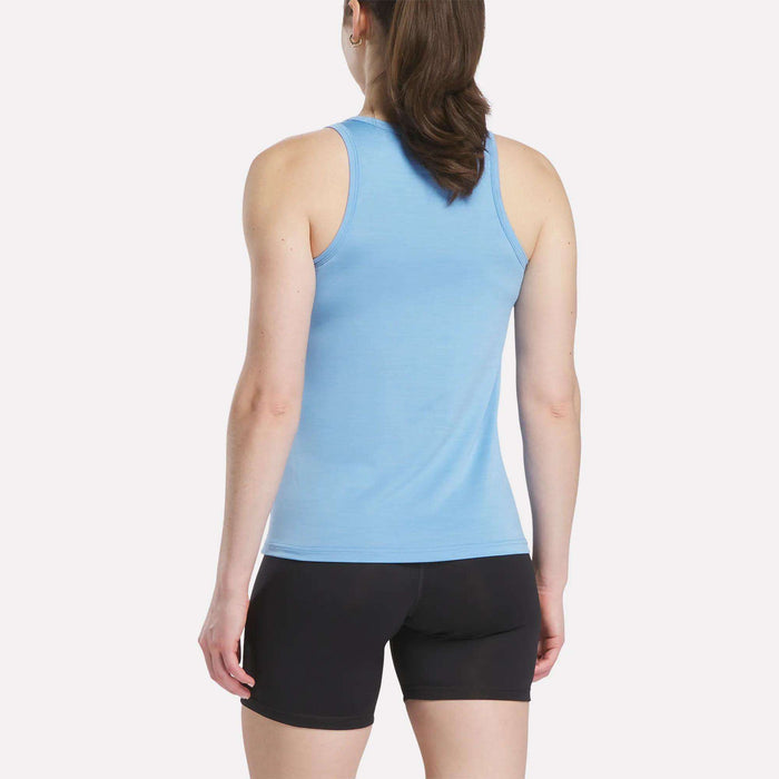 A woman with long brown hair wears a Reebok Women's Marled Performance Tank Top in light blue and black shorts, standing with her back to the camera against a plain white background.